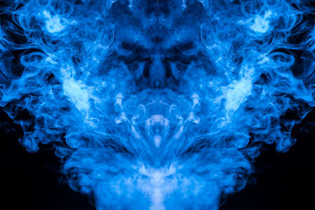 A multi-colored pattern of blue smoke of a mystical shape in the form of a face and a ghost's head or a strange creature on a black isolated background. Abstract pattern in of waves and steam.の写真素材