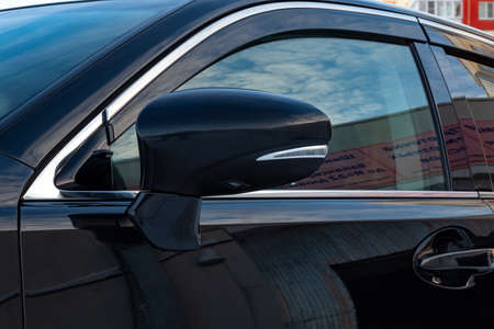 Close-up of the mirror of the car body  black sedan on the street parking in the snow.の写真素材