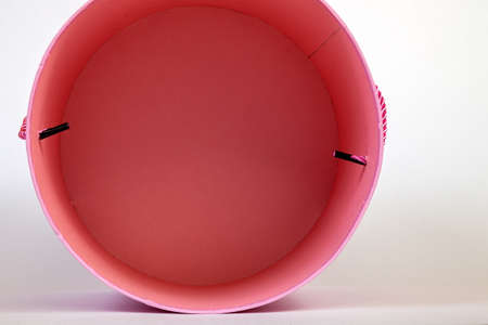 Top view of a pink pink round cardboard box empty inside for gift wrapping on a white background close-up and with a ribbon in the form of a pen on the side.の写真素材