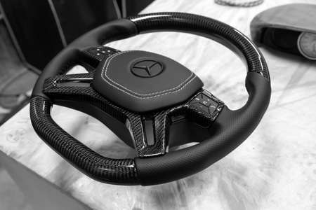 Novosibirsk, Russia - 08.01.2018: Carbon steering wheel of a black car in the workshop tightened and perforated with natural leather close up with the brand sign of Mercedes covered with matte paintのeditorial素材