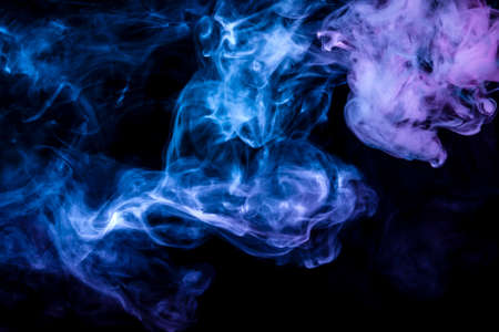 Clubs of colored smoke of blue and pink color on a black isolated background in the form of soft clouds from the vapeの写真素材