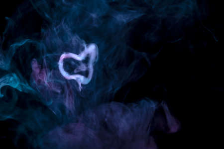 Black background with scattered blue and pink smoke and a gray ring from steam that was made during smokingの写真素材