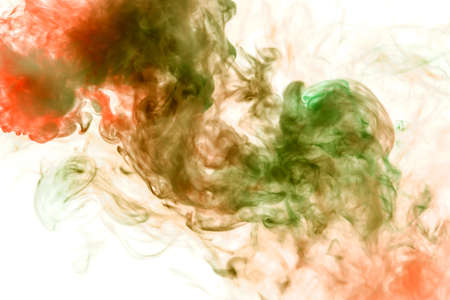 Translucent, thick smoke, illuminated by light against a white background, divided into two colors: green and orange, burns out, evaporating from a pair of vape. T-shirt print.の写真素材