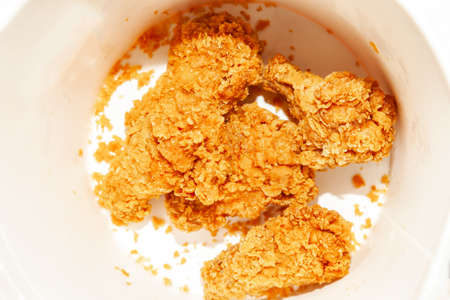 Close-up of appetizing fried chicken wings made from fresh meat at the bottom of a brown-breading bucket, a favorite fast-food for dinner and in the cinema.の写真素材