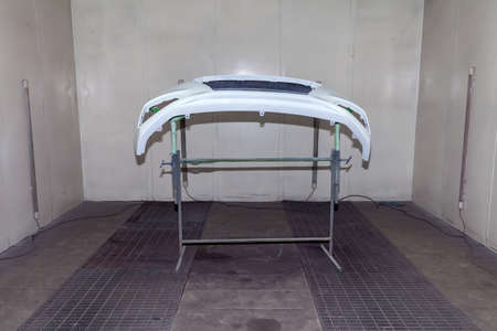 Repair of the rear bumper of a white car after an accident with the help of multi-colored putty in a...