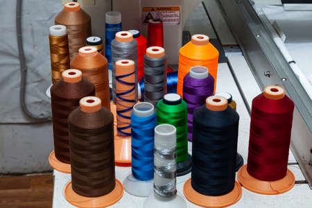 A large number of reels with colored threads in a workshop for sewing and hauling textiles for the...