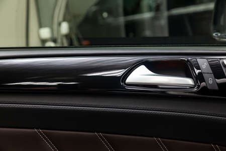 A close-up view of a part of the interior of a modern luxury car with a view of a silver-colored...