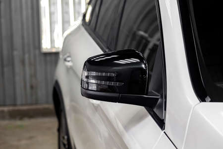 Close-up of the black side mirror of the car body in the design of a white suv with turn light