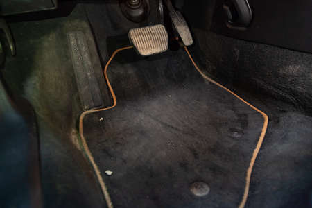 Dirty car floor mats of black carpet with gas pedals and brakes in the workshop for the detailing vehicle before dry cleaningの写真素材