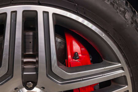 Close-up on a part of an aluminum wheel through the spokes of which a perforated brake disc and a...