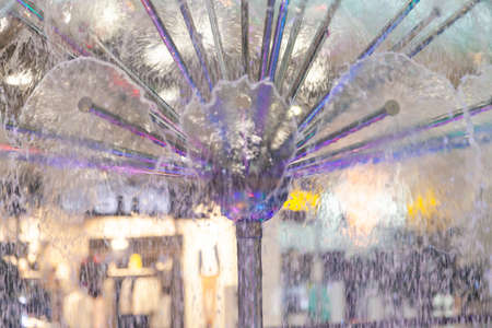 Close-up on a fountain with colored lights in the form of a dome spraying water in different...