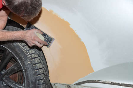 Preparation for painting a car element using emery sender by a service technician leveling out before applying a primer after damage to a part of the body in an accident in the vehicle workshopの写真素材