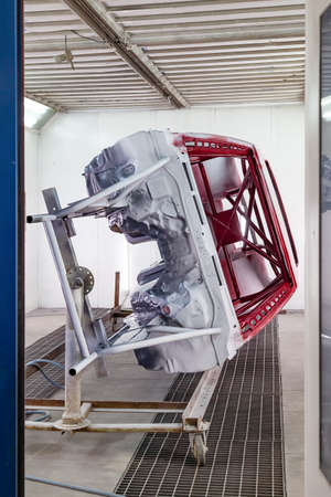 Vertical view from the door of painting in red and black color of the inside of the frame of the car disassembled after the accident in the workshop for body repair and tuning of vehiclesの写真素材