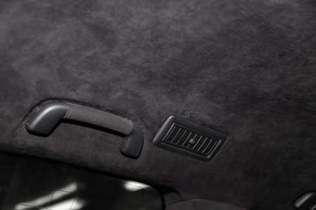 The ceiling of the SUV car pulled by black soft material alkantara in the workshop for tuning and styling the interiorof the vehicles with sunroof. Auto service industry.の写真素材