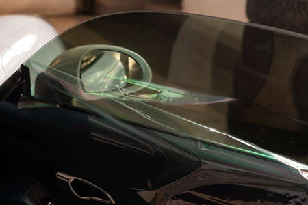 The process of tinting the glass of the car in the workshop for the installation of additional...