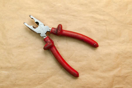 Open pliers with red rubber handles used during work to clamp parts for craftsmanship in the tool...