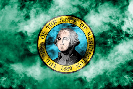 The national flag of the US state Washington in against a gray smoke on the day of independence in different colors of blue red and yellow. Political and religious disputes, customs and delivery.の写真素材