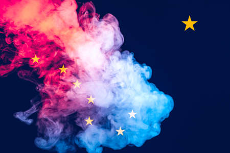 The national flag of the US state Alaska in against a gray smoke on the day of independence in different colors of blue red and yellow. Political and religious disputes, customs and delivery.の写真素材