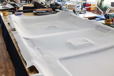 Gray ceiling lining removed from the car for tuning and bracing with grey soft material on a table...