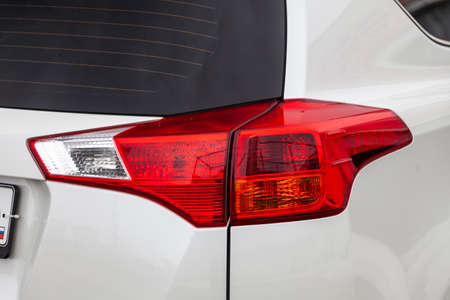 Close-up on the rear brake light of red color on a white car in the back of a suv after cleaning,...