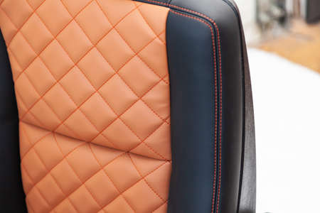 A view of a part of the interior of the car seat from leather of black and beige color, stitched...