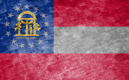 The national flag of the US state Georgia in against a gray textile rag on the day of independence in different colors of blue red and yellow. Political and religious disputes, customs and delivery.の写真素材