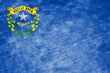 The national flag of the US state Nevada in against a gray textile rag on the day of independence in different colors of blue red and yellow. Political and religious disputes, customs and delivery.の写真素材