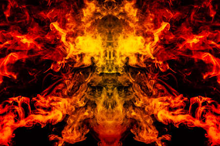 Smoke of different orange and red colors in the form of horror in the shape of the head, face and eye with wings on a black isolated background. Soul and ghost in mystical symbolの写真素材