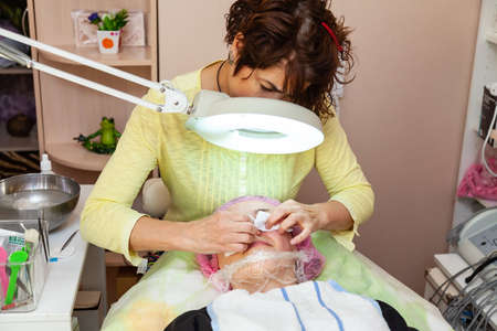 A young girl is lying on a couch during cosmetic procedures with a mask on the face above which...
