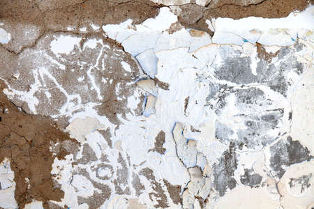 Background with the image of the old white wall with falling off and exfoliated paint and plaster on...