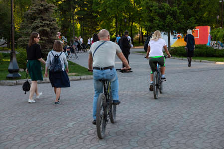 Elderly couple men and women ride bicycles during a walk in the park among a large number of people...