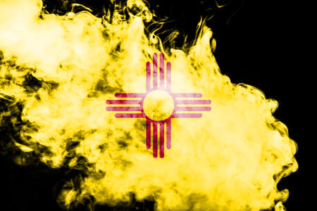 The national flag of the US state New Mexico in against a gray smoke on the day of independence in...