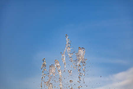 City fountain with splashes and tops jets of water frozen in the air on a clear summer day against...
