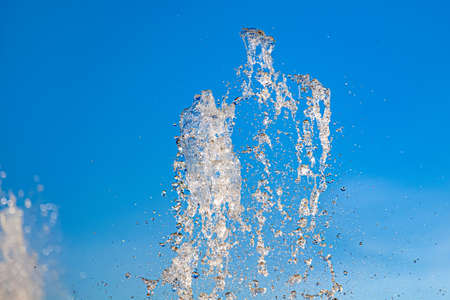 City fountain with splashes and tops jets of water frozen in the air on a clear summer day against...
