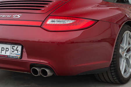 Novosibirsk, Russia - 07.17.2019: Rear taillamp and exhaust view of car Porsche 911 Carrera 4s with dark gray interior in excellent condition in a parking against city landscapeのeditorial素材