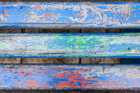 Close-up on a wooden flat surface with old peeling paint of different colors with cracks on three boards. Blue, green and red color on the tree.の写真素材