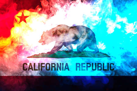The national flag of the US state California in against a gray smoke on the day of independence in different colors of blue red and yellow. Political and religious disputes, customs and delivery.の写真素材