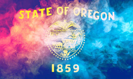 The national flag of the US state Oregon in against a gray smoke on the day of independence in different colors of blue red and yellow. Political and religious disputes, customs and delivery.の写真素材