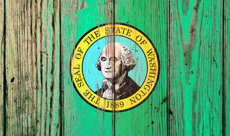 Washington US state national flag on a gray wooden boards background on the day of independence in different colors of blue red and yellow. Political and religious disputes, customs and delivery.の写真素材