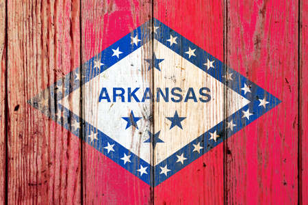 Arkansas US state national flag on a gray wooden boards background on the day of independence in different colors of blue red and yellow. Political and religious disputes, customs and delivery.の写真素材