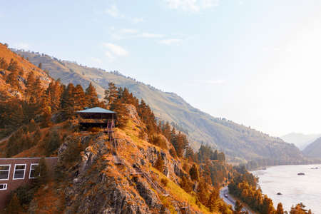 A landscape with a picturesque place in the mountains at the top of the cliff stands a gazebo with a...
