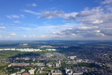 Aerial view of the cityscape with a lot of houses and buildings on a summer clear day under a blue sky with gray clouds in Novosibirsk.の写真素材
