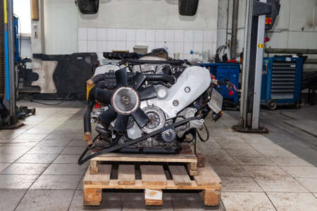 Replacement engine used on a pallet mounted under raised car on lift  for installation after a...