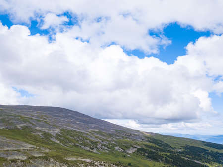 landscape of the ridge covered with green trees and view a valley flooded with sunlight ,pasture, with dense clouds in the sky. summer day in the mountains of the Altaiの写真素材