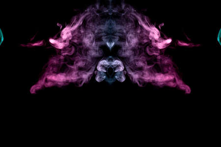 Smoke of different blue, red and pink colors in form of horror in the shape of the head, face and eye with wings on a black isolated background. Soul and ghost in mystical symbol. Print for clothes.の写真素材