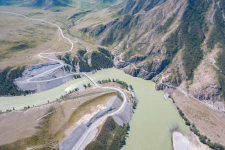 Landscape of the mountain chain of the Altai covered with green trees and rocks, with the turquoise Katun River and its rapids on a sunny summer day and a blue sky with white clouds. Tourist route.の写真素材