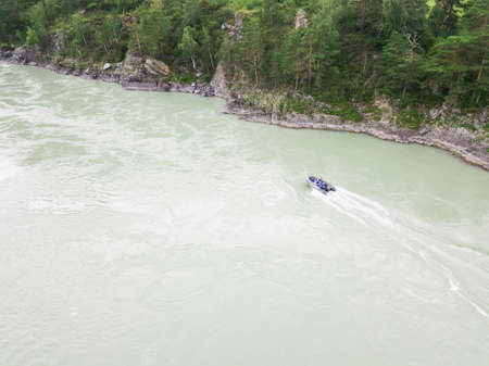 Aerial view of a rubber motor boat sailing on a green river in the mountains between rocks and cliffの写真素材