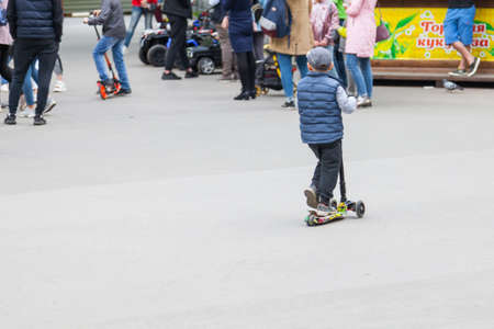 Novosibirsk, Russia - 06.02.2019: One boy in a cap roll on a scooters pushing off a road with smiles...