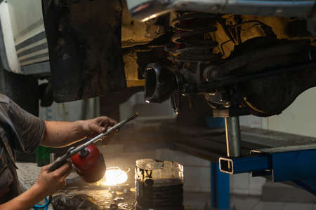 Car suspension repair in the back of a white SUV on a lift with a wheel removed and a disassembled suspension. Auto service industry and maintenance.の写真素材