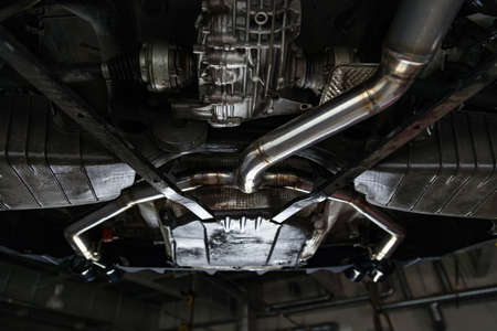 Fabrication and installation of a stainless steel car exhaust pipe with a bifurcation and a louder sound with a color weld under bottom. Tuning and auto service industry.の写真素材